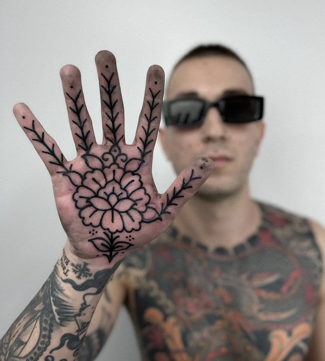 Bold black floral palm tattoo with ornamental linework