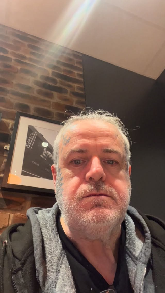 Blue geometric facial tattoo accents on rugged face.