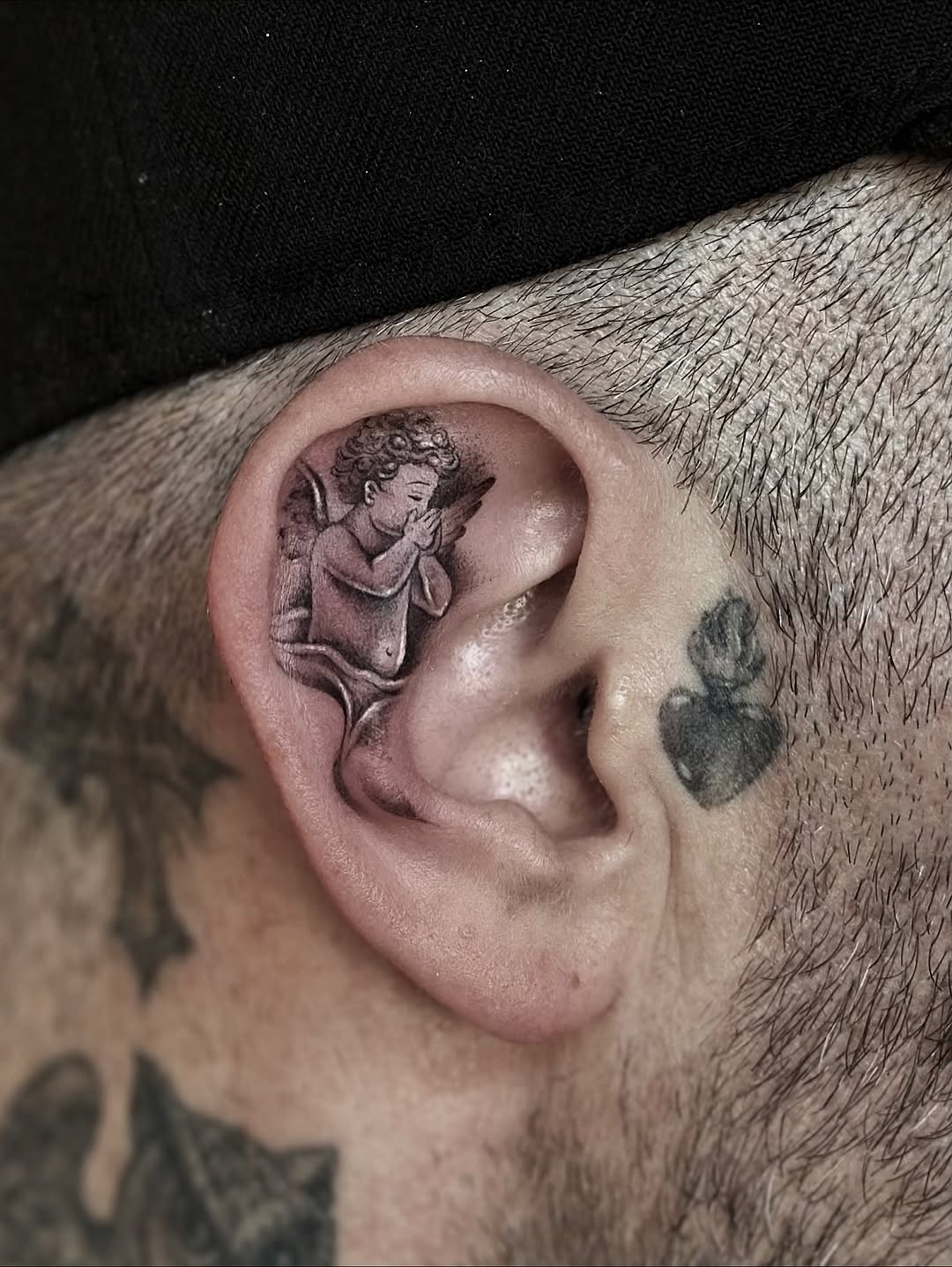 Praying cherub inside ear, soft grayscale shading