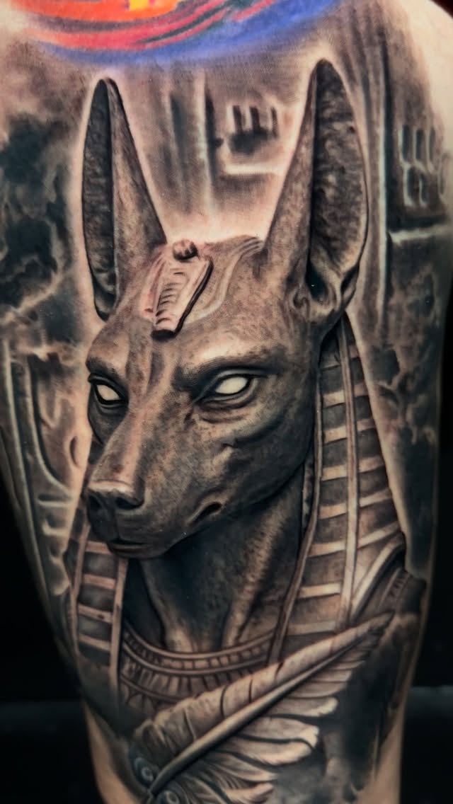Hyper-detailed black-and-gray Anubis jackal portrait on thigh