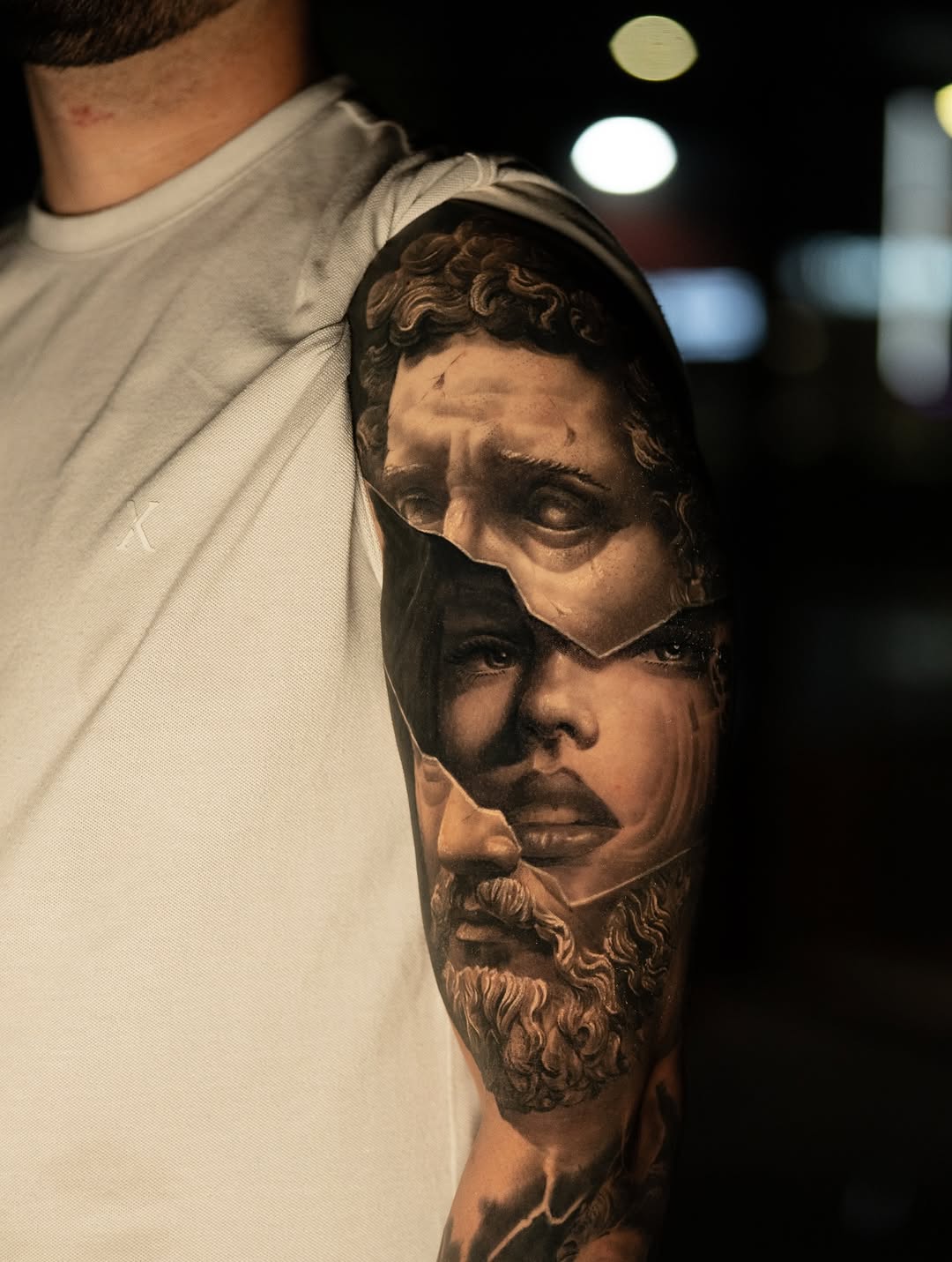 Hyper-realistic black-and-gray bust mosaic across upper-arm.