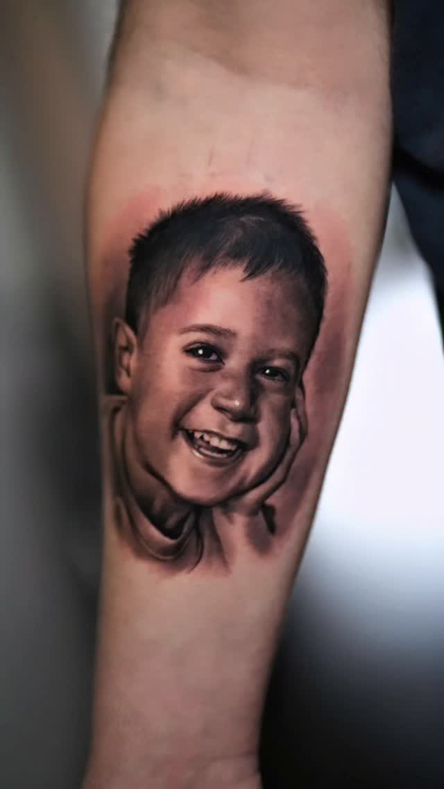 Hyper-realistic grayscale portrait of smiling child on forearm