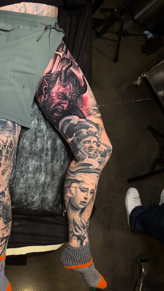 Dramatic black-and-gray leg sleeve with horned demon and serene busts