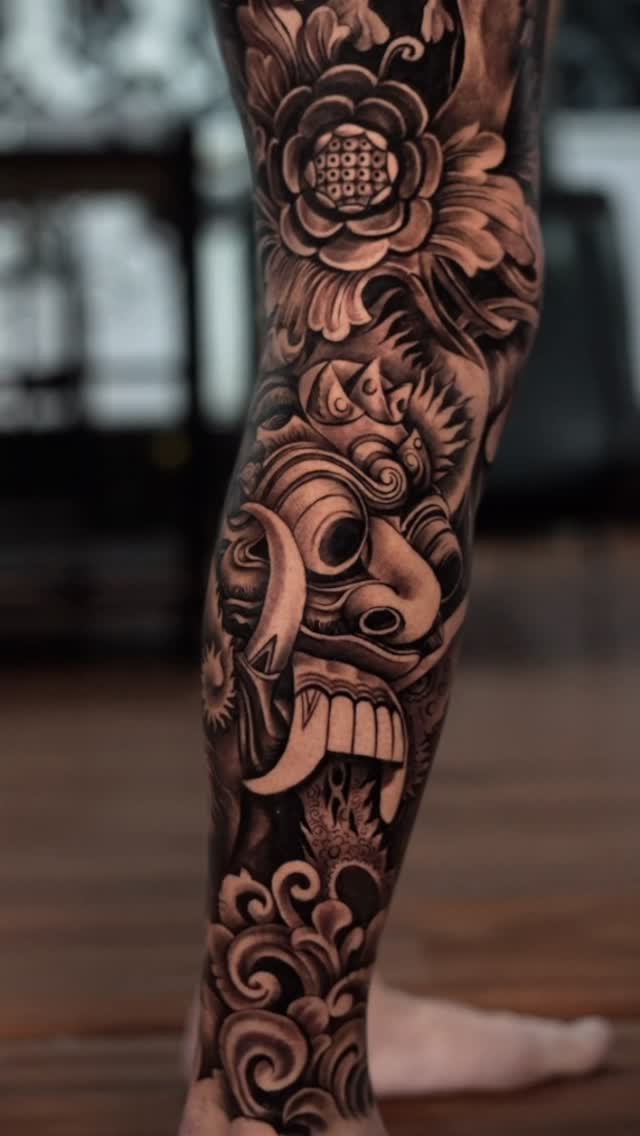 Hannya-inspired demon mask amid swirling floral blackwork on calf