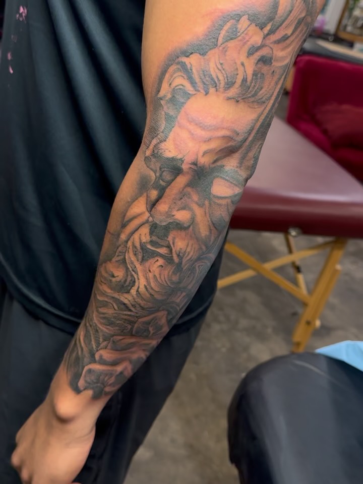 Hyper-detailed black-and-gray portrait on the forearm.