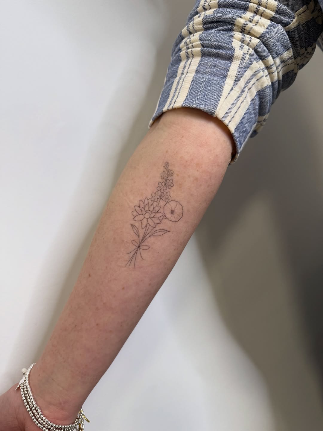 Delicate fine-line floral bouquet on forearm.