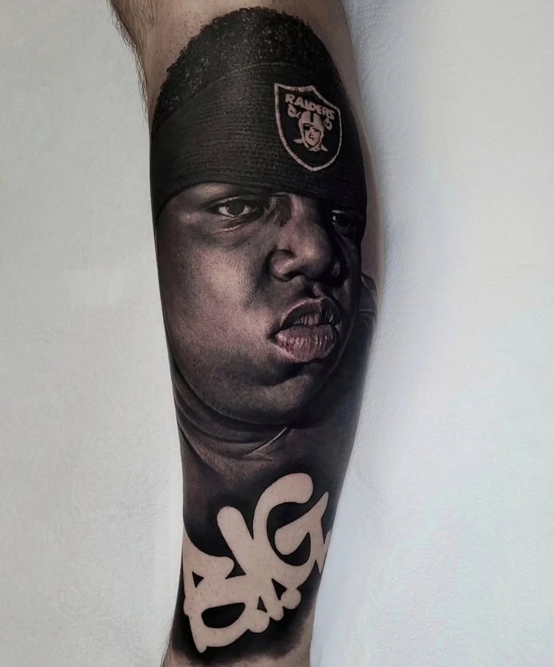 Hyper-realistic grayscale forearm portrait with Raiders headband