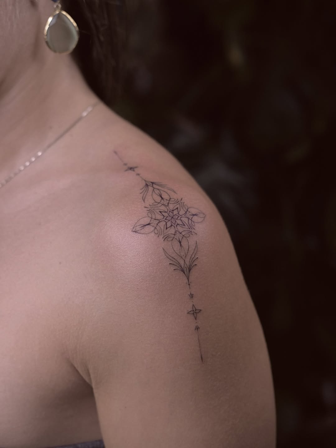 Delicate fine-line floral cascade along the shoulder.