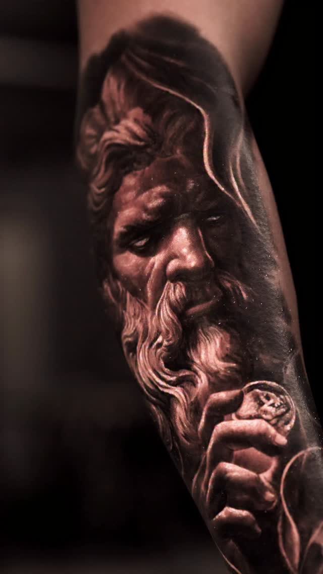 Surreal black-and-gray Hades statue portrait on forearm