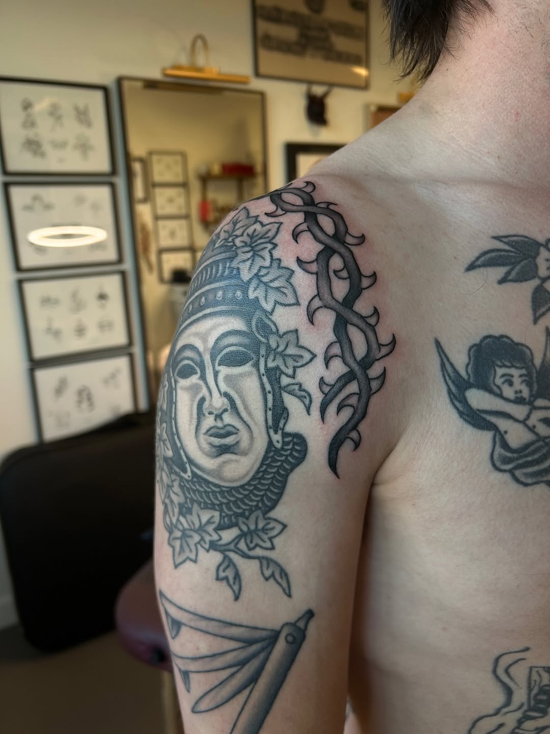 Bold blackwork mask-face with twisting vines and leaves.