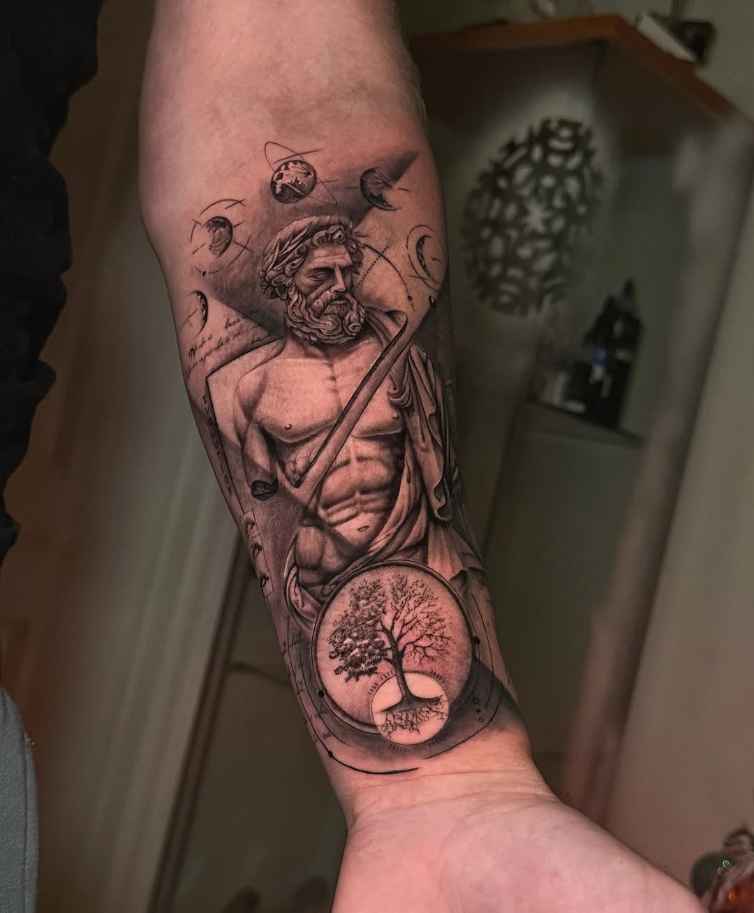 Dramatic black-and-gray classical god figure with orbital motifs