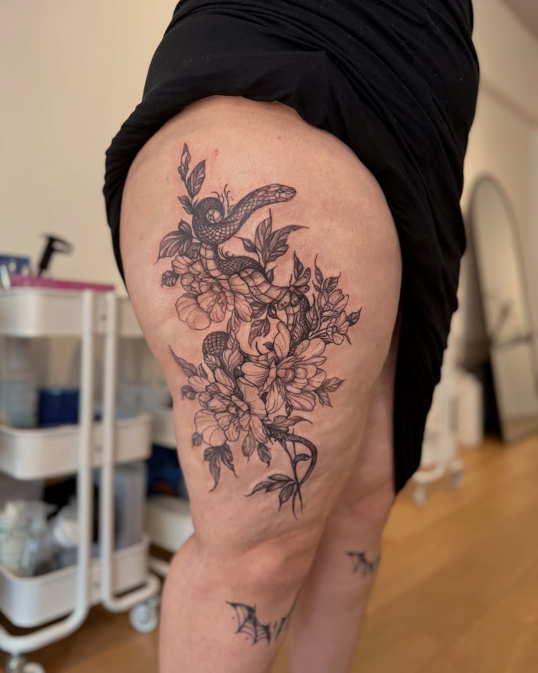 Intricate black-and-gray botanical snake thigh piece with fine-line