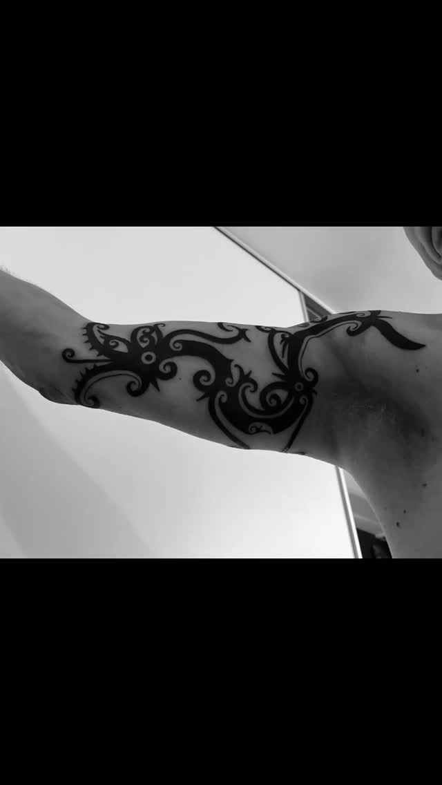 Bold black tribal dragon-dog band on forearm