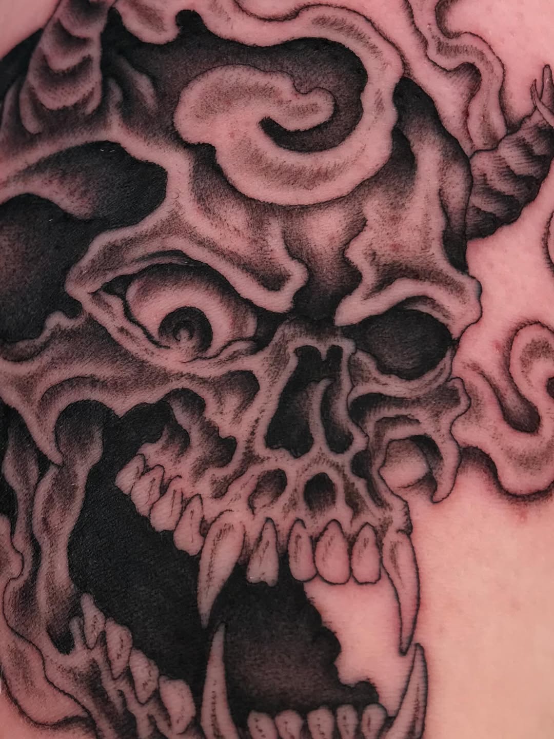 Intense blackwork skull with bold shading and jagged teeth