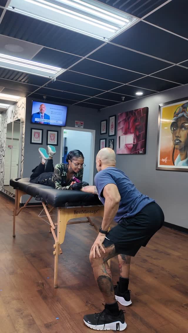 Focused tattoo session in bright shop; calf ink underway.