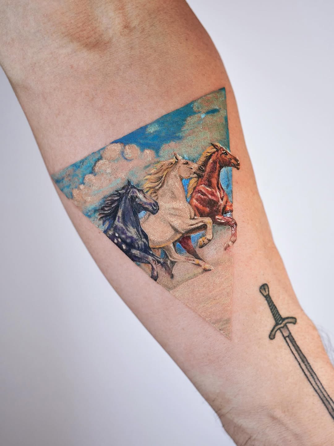 Vivid trio of galloping horses in a triangular watercolor panel