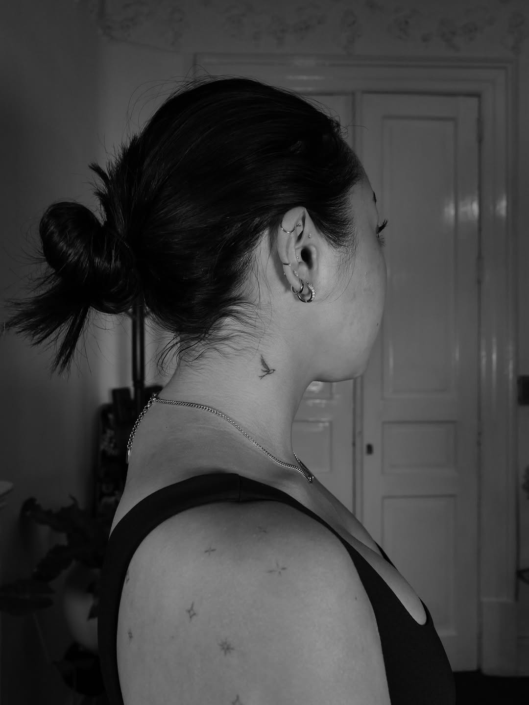Delicate back-of-neck bird tattoo in minimalist linework