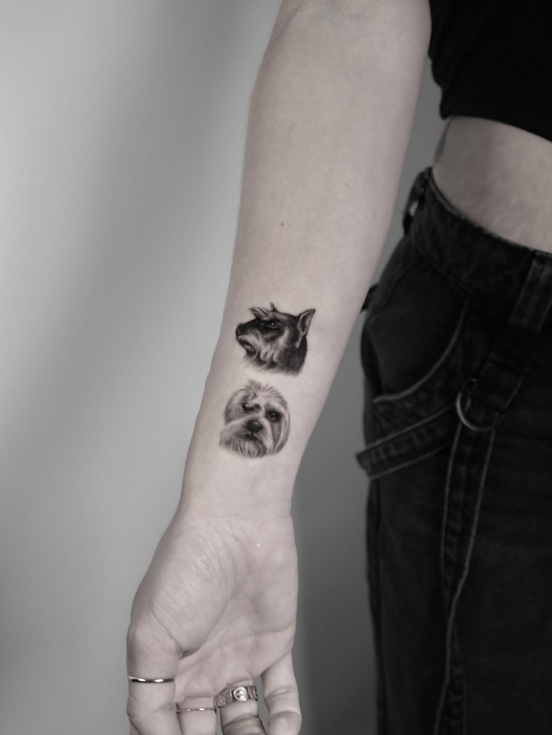 Two realistic dog heads in grayscale on forearm