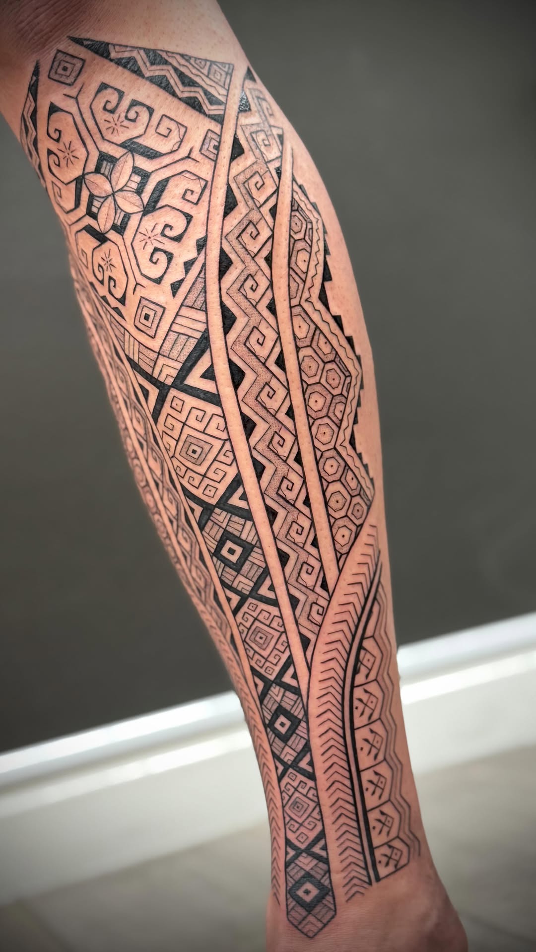 Intricate geometric Polynesian-inspired leg sleeve in bold black.