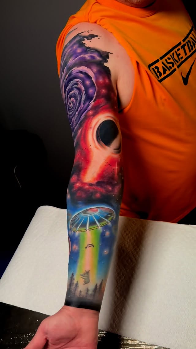 Vibrant space-themed forearm scene with UFO and rainbow beam