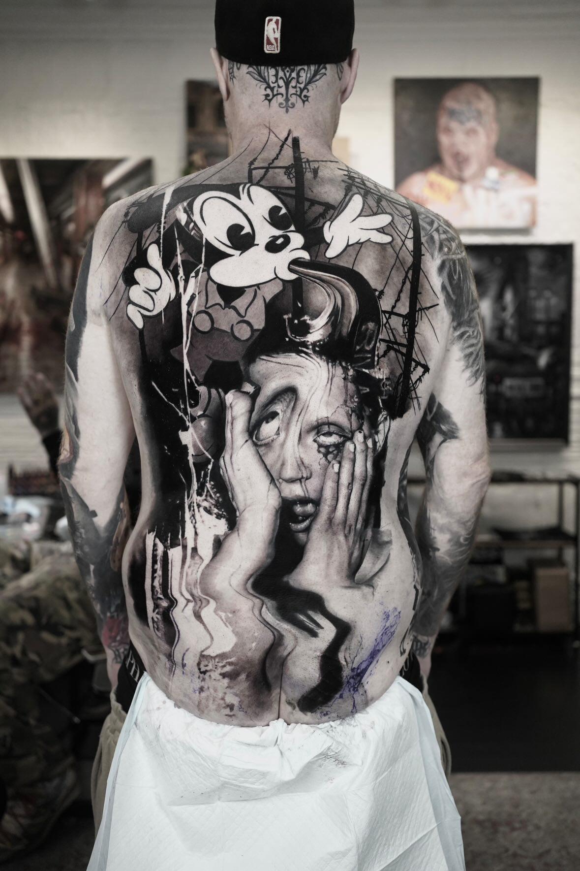 Monumental black-and-gray backpiece with distorted figure and cartoon.