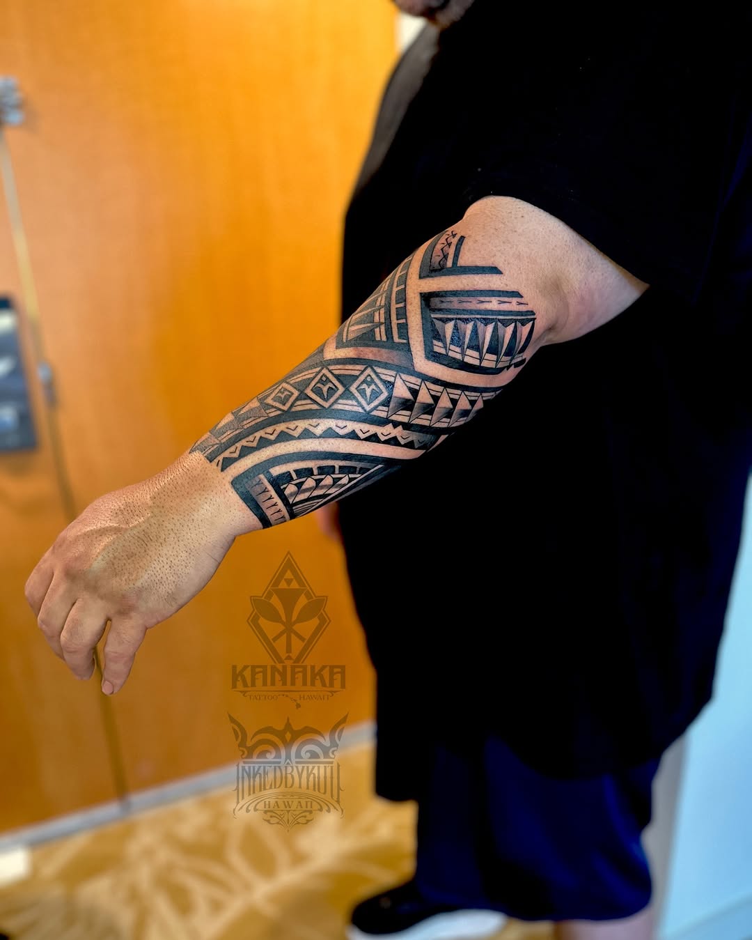 Bold Polynesian-inspired tribal forearm sleeve with geometric patterns