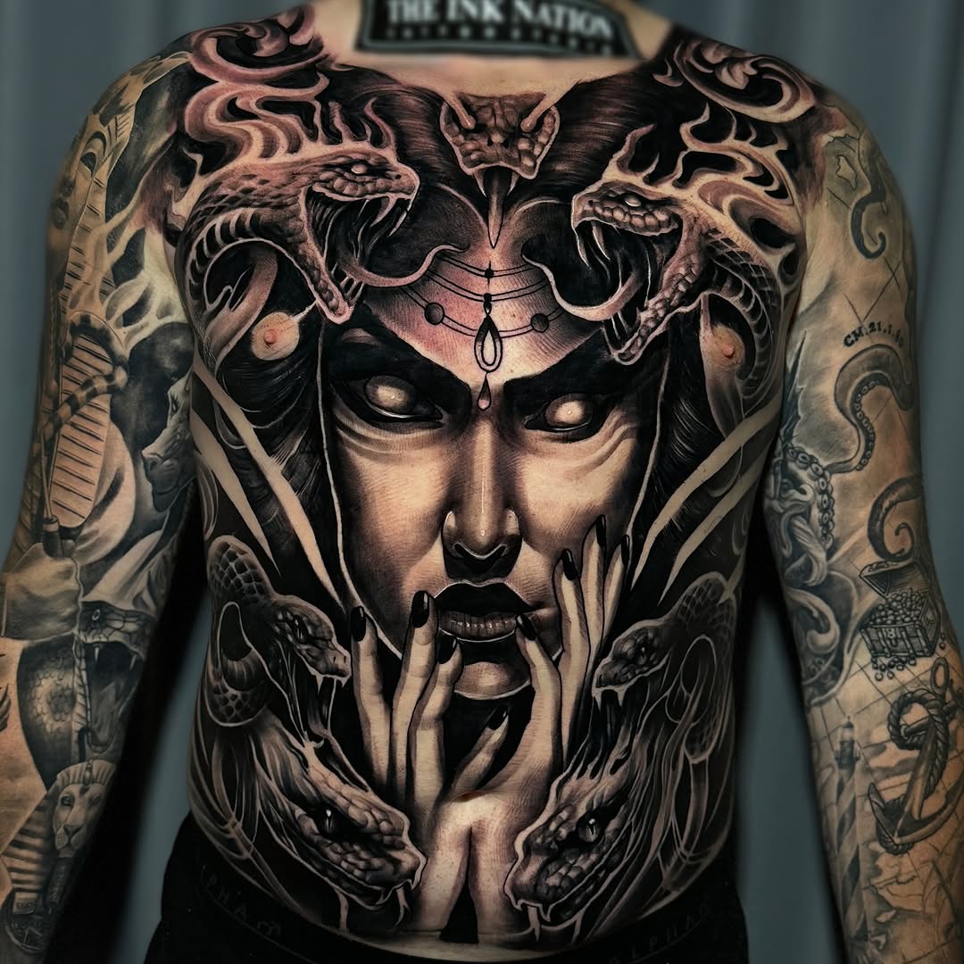 Dark, hyper-detailed back piece with crowned female visage and serpents