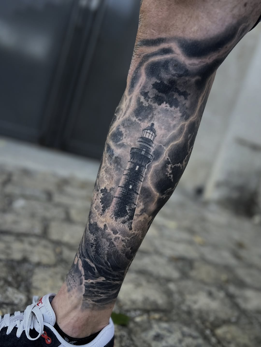 Monochrome lighthouse emerging through stormy clouds and waves