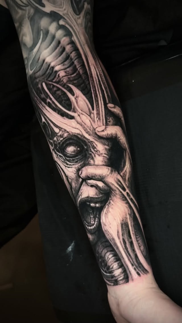 Hyper-detailed black-and-gray horror face on forearm