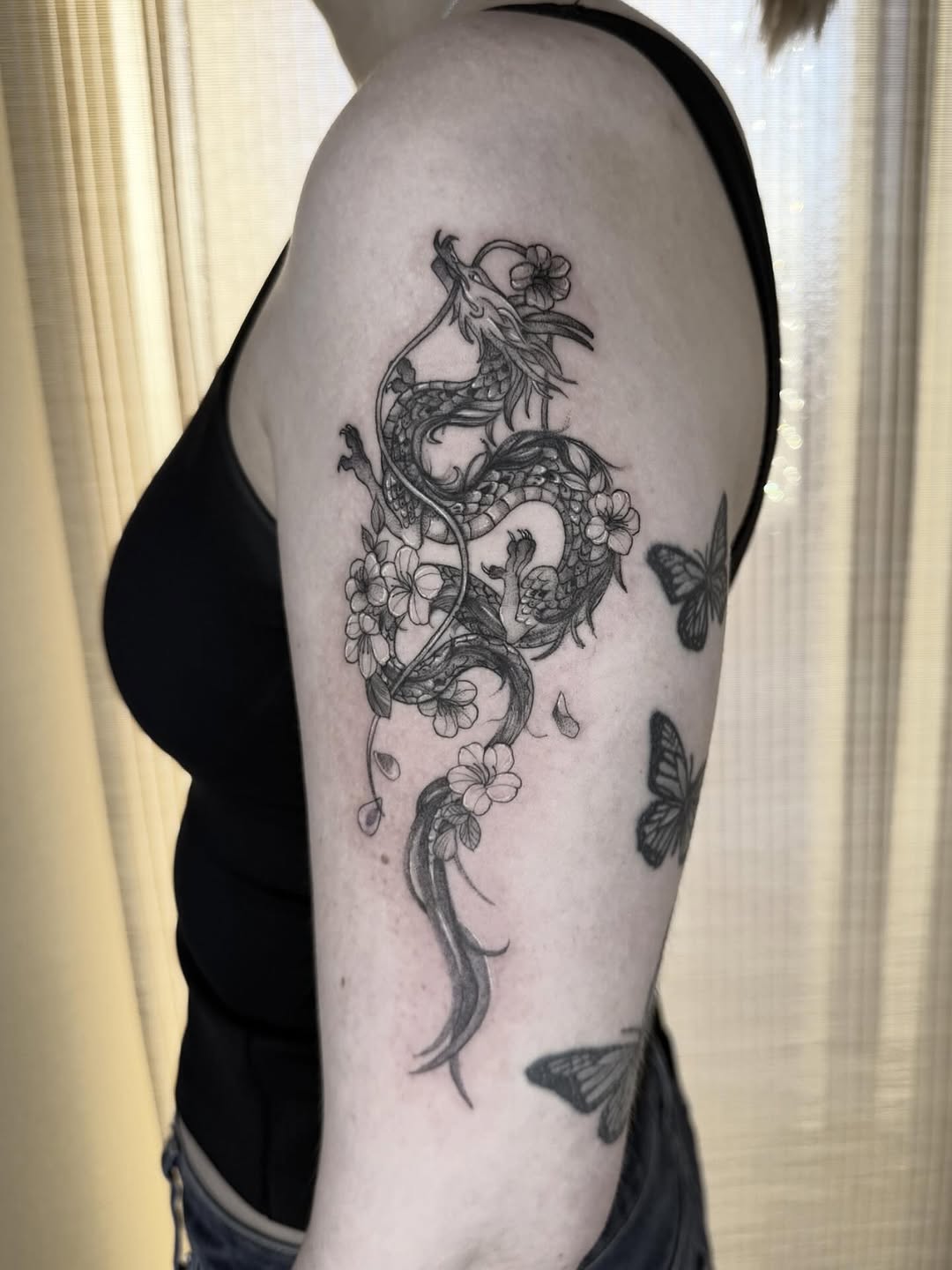 Intricate black-and-gray dragon entwined with blooming cherry blossoms