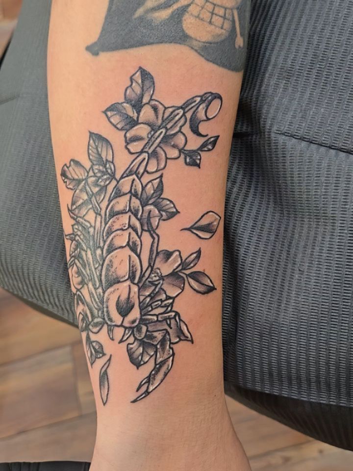 Delicate botanical forearm piece with fine-line shading