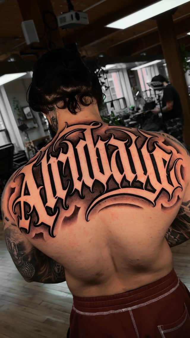 Bold blackletter surname spans the upper back with shading
