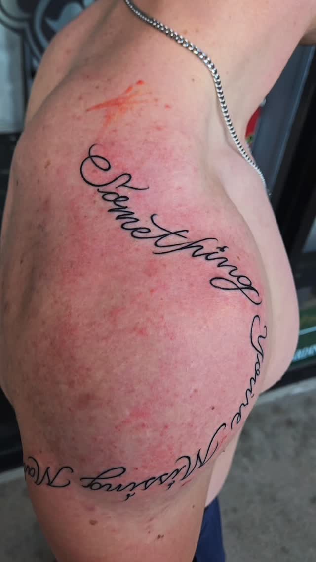 Elegant freehand cursive script wrapping the shoulder.