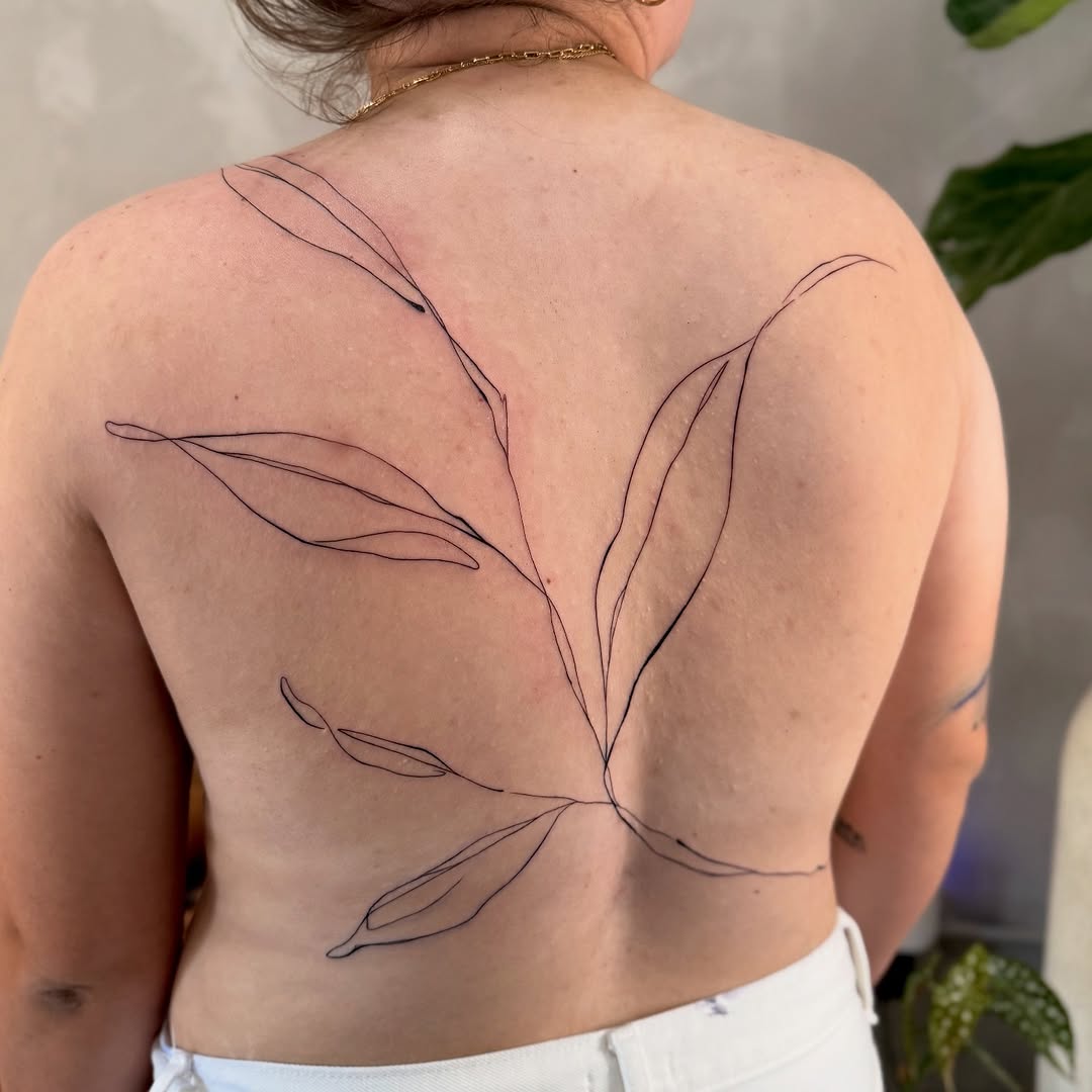 Delicate fine-line botanical back piece with flowing leaves