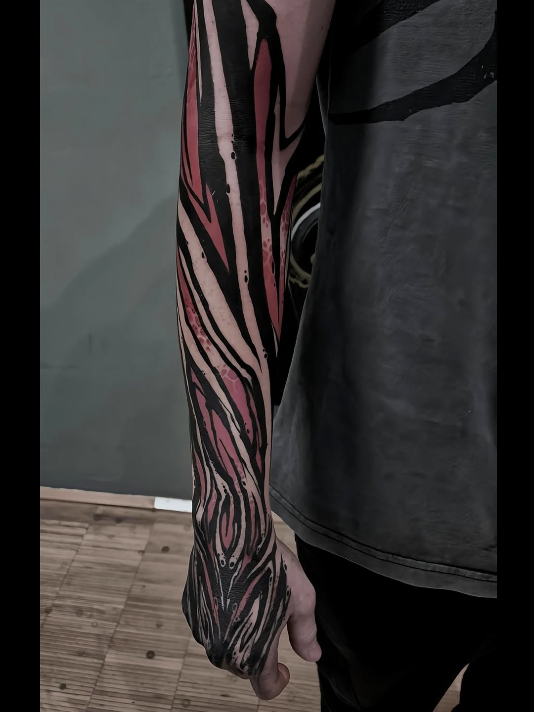 Bold pink-black zebra-stripe blackwork forearm sleeve.