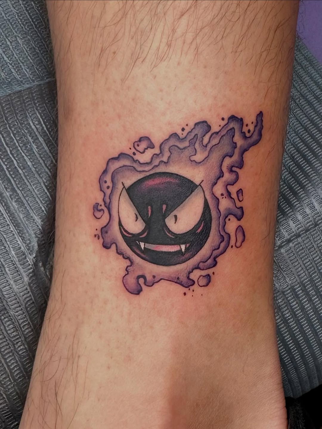 Smirking ghost Pokémon-inspired orb surrounded by violet haze