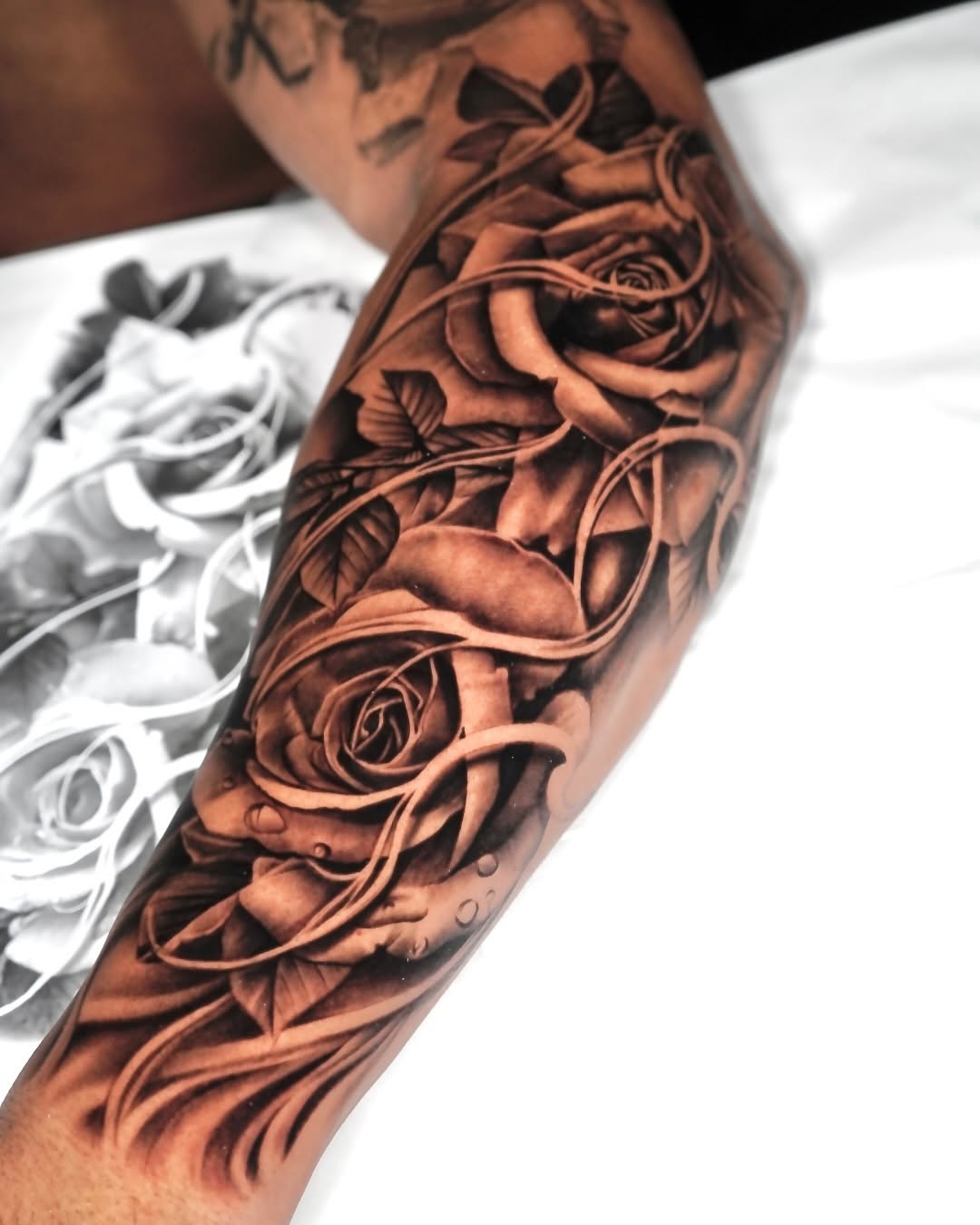 Hyper-realistic black-and-gray roses wrap the forearm.