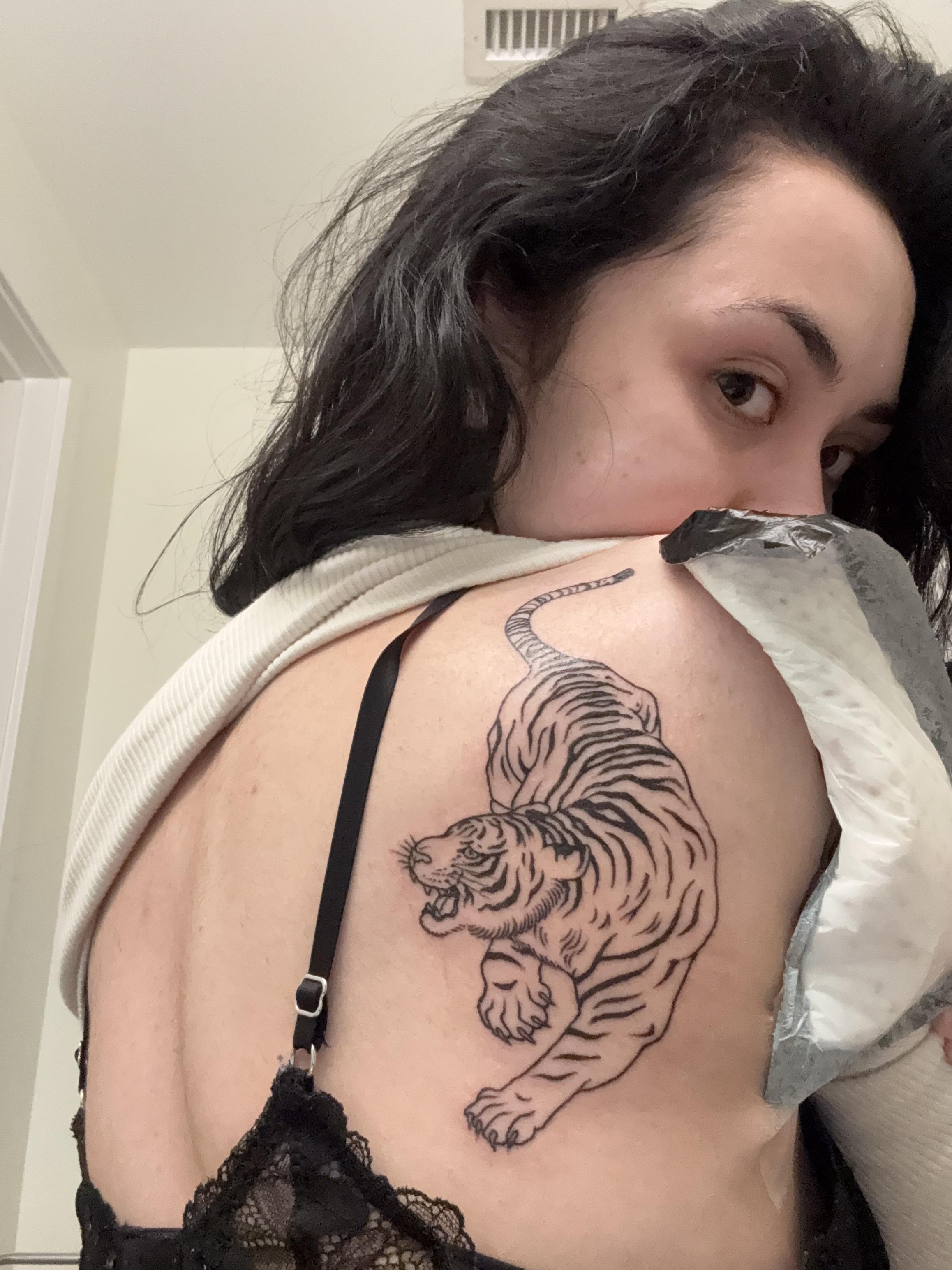 Bold tiger in dynamic linework across the shoulder blade.