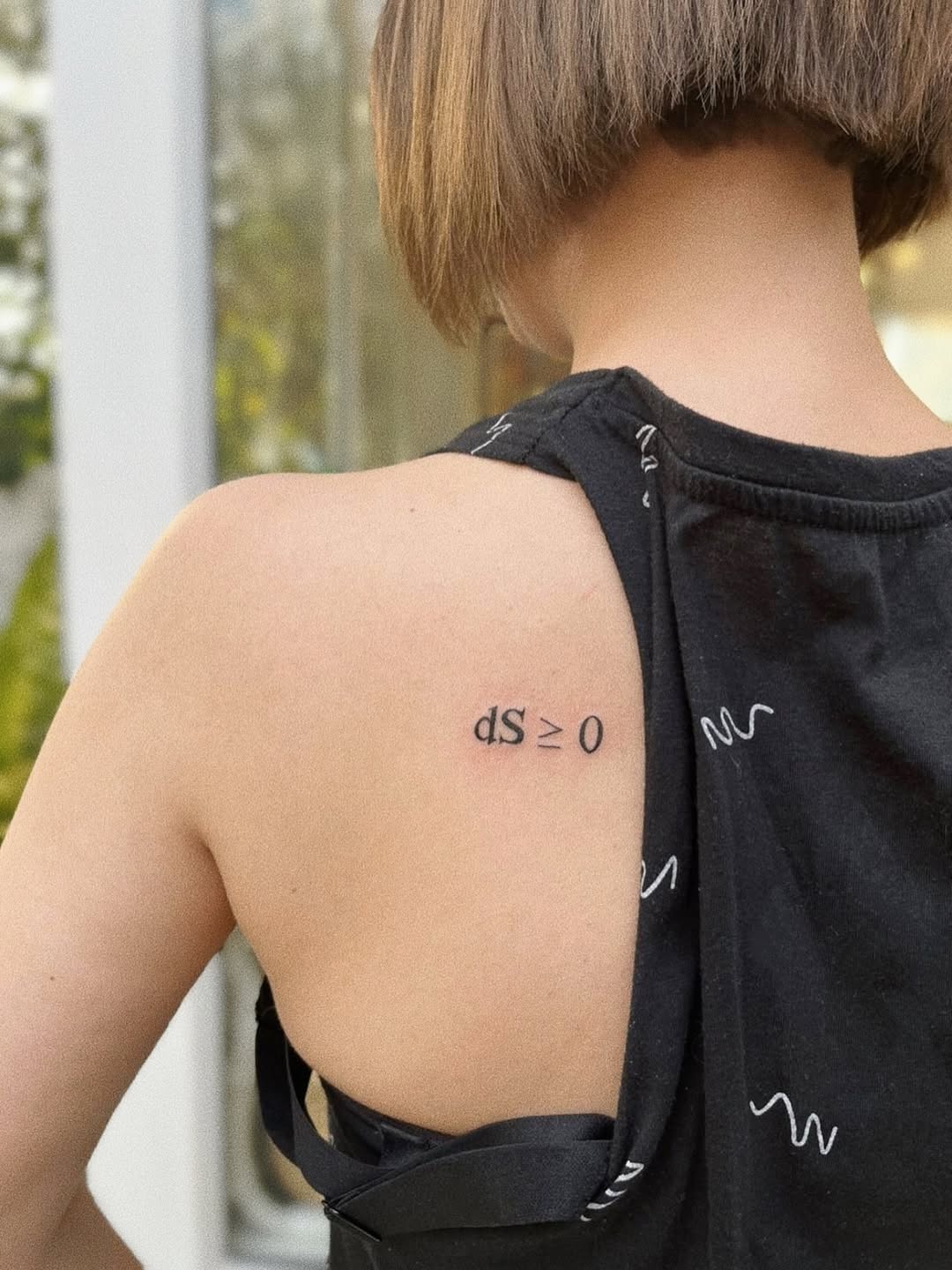 Minimalist black-ink equation tattoo on shoulder