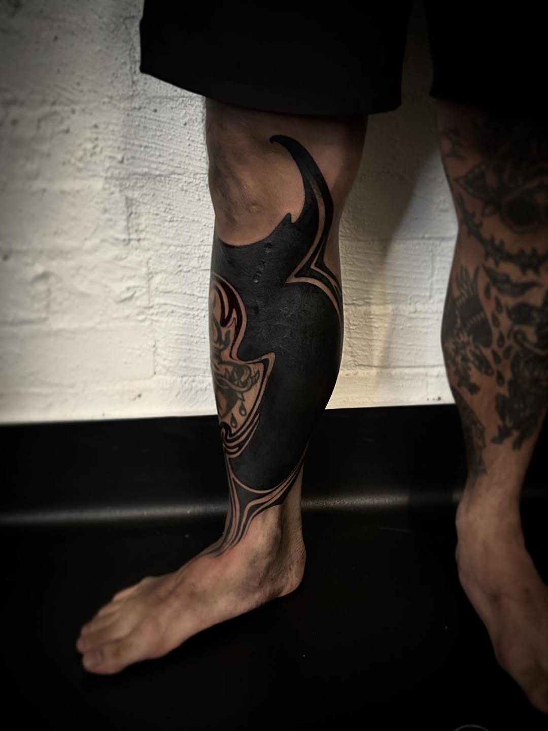 Sinuous blackwork leg piece with flowing negative-space outlines