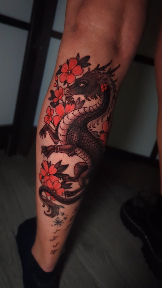Bold blackline dragon entwined with crimson blossoms on calf