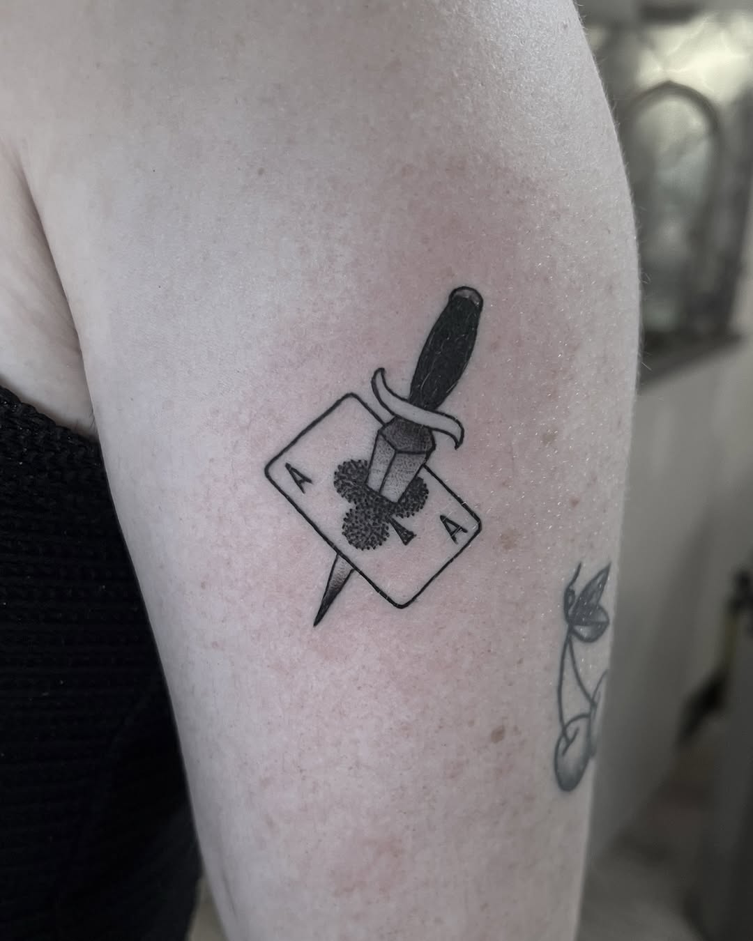 Bold dagger pierces a playing card with a clover emblem