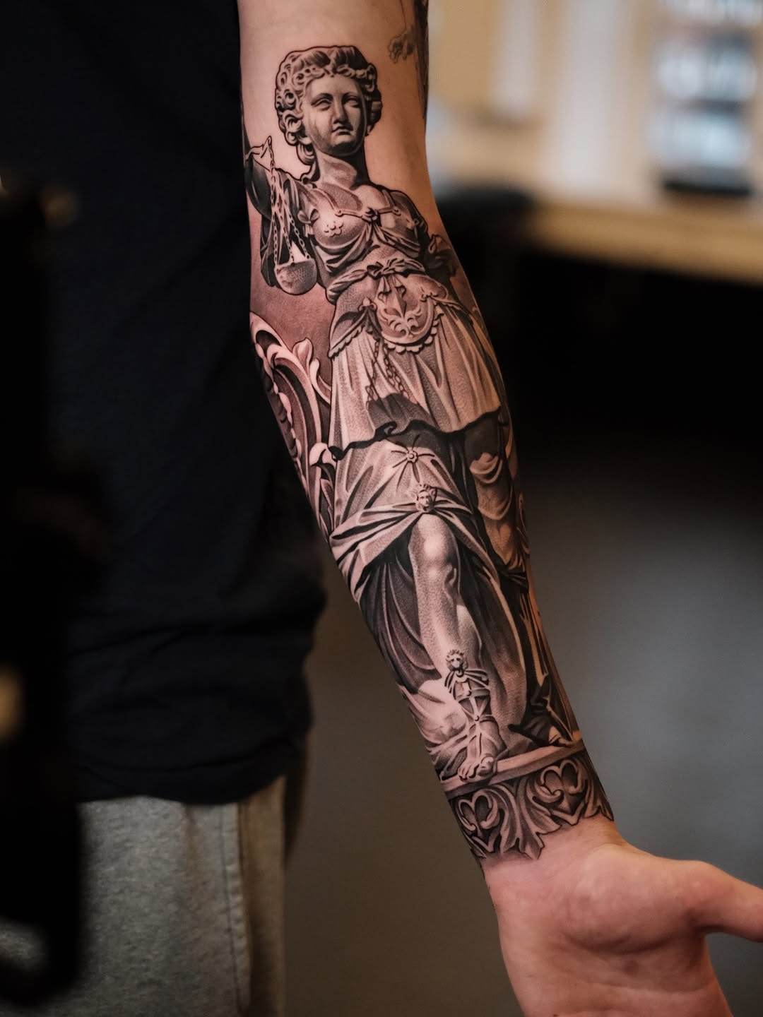 Bold black-and-gray realism of a classical statue forearm sleeve