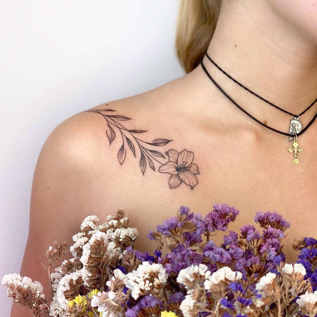 Delicate linework floral tattoo along shoulder-collarbone.