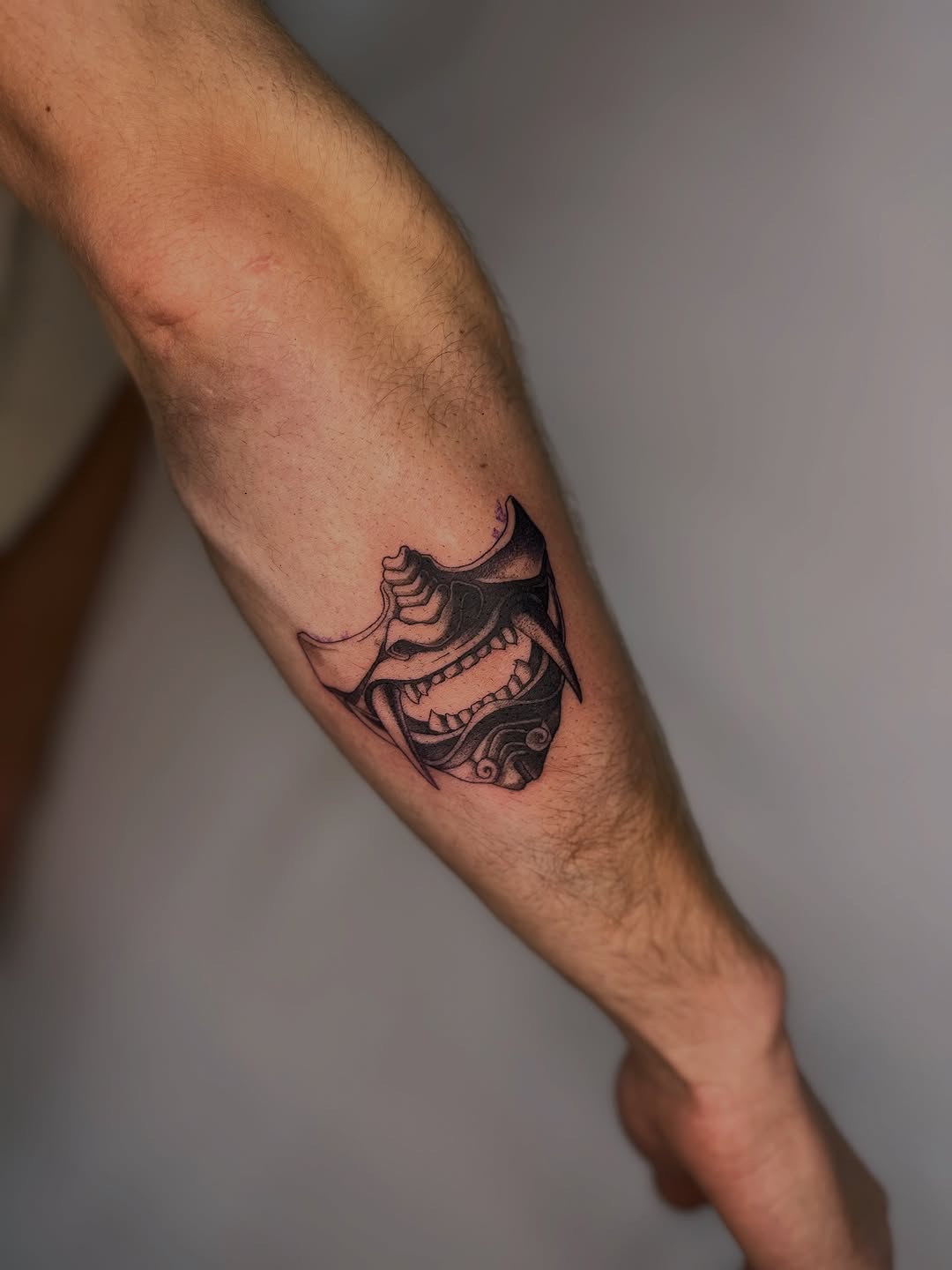 Oni mask blackwork forearm tattoo with bold linework