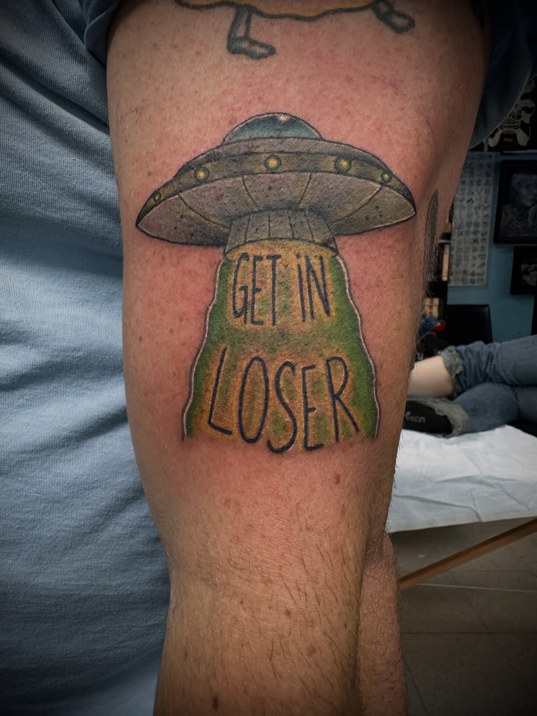 Whimsical flying saucer with bold 'GET IN LOSER' text