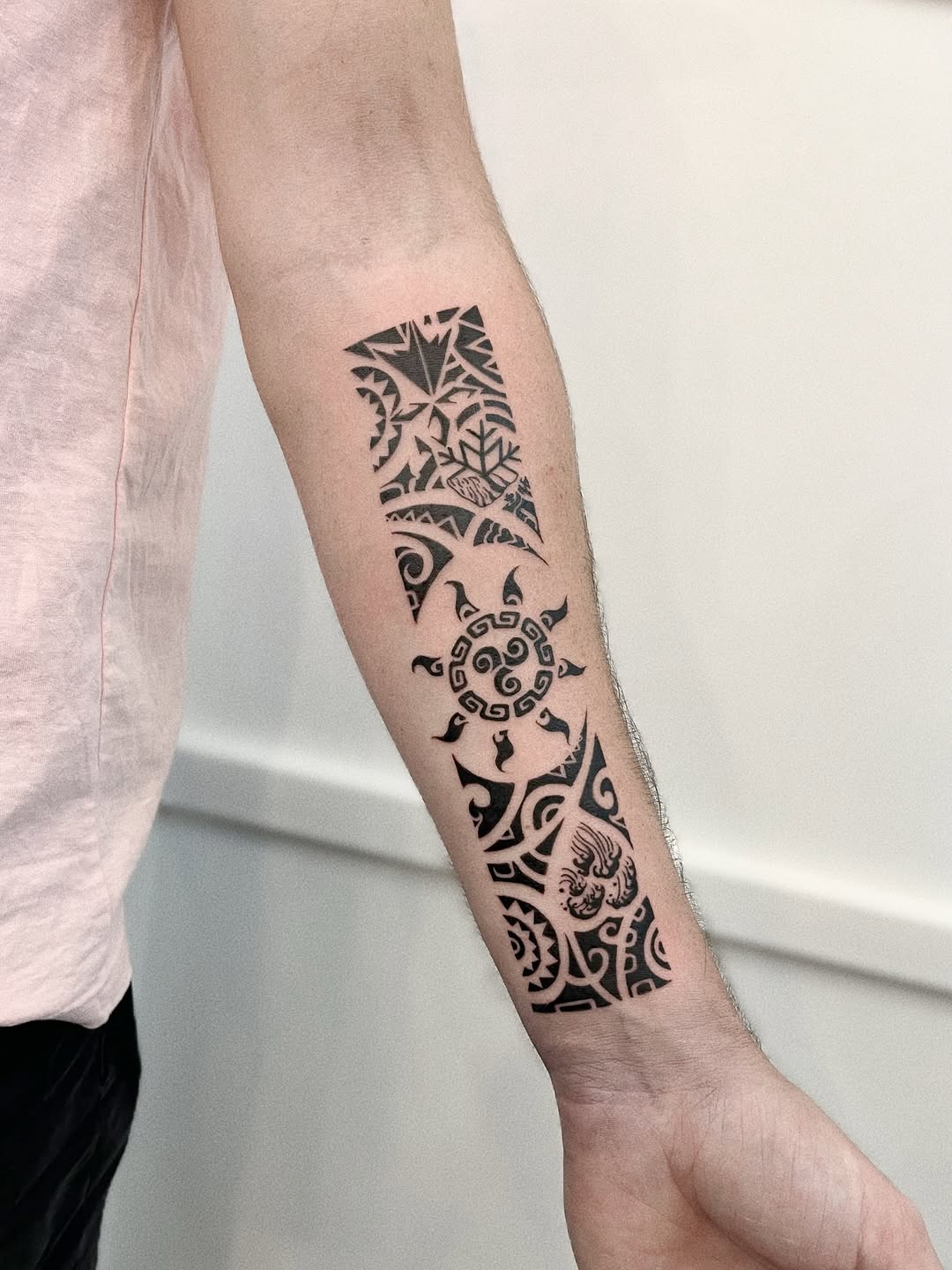 Polynesian-inspired black tribal forearm tattoo with geometric patterns