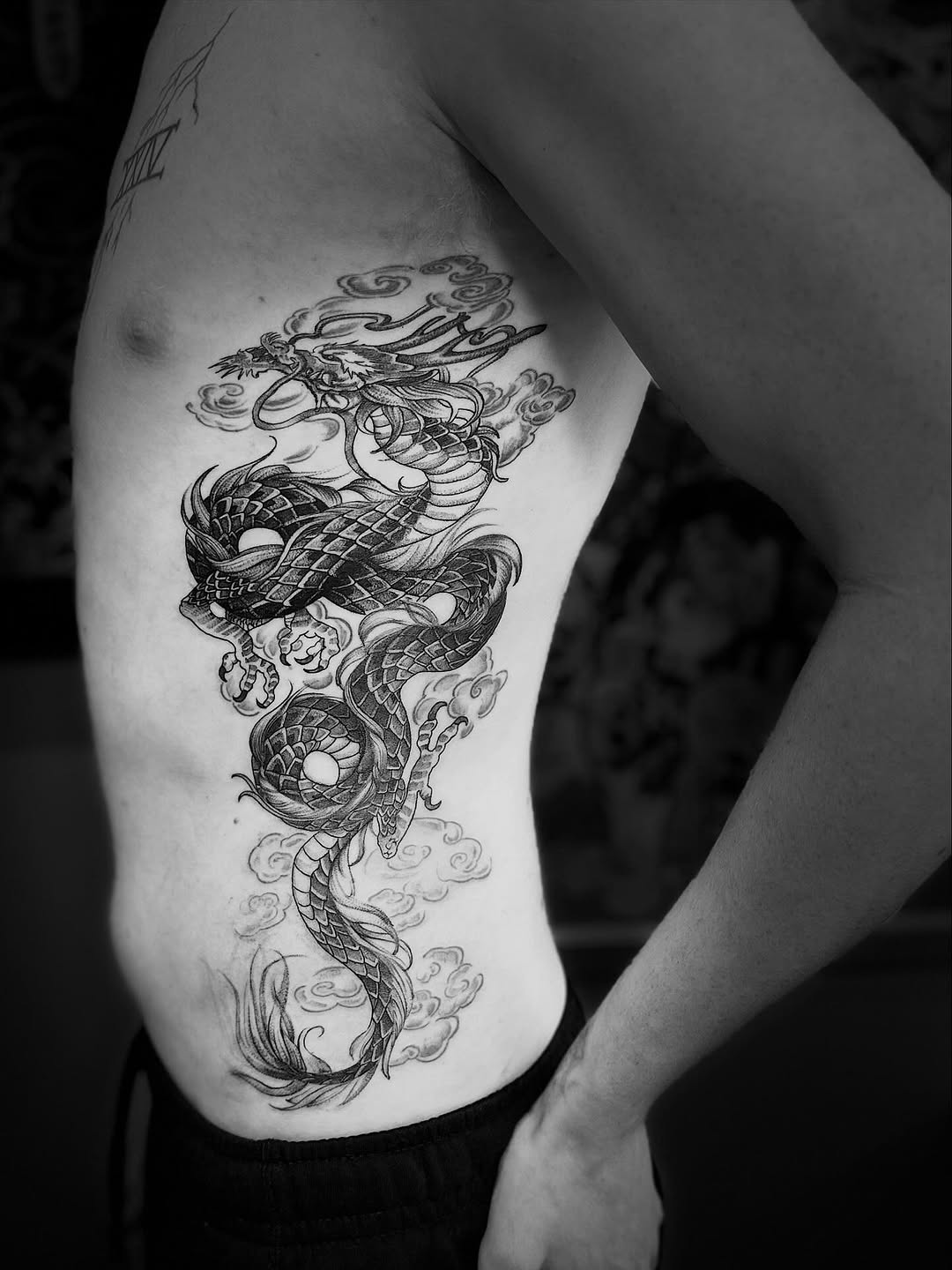 Intricate black-and-gray dragon coils along the ribcage