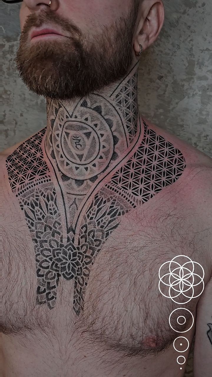 Intricate geometric chakra chestpiece spanning neck and chest.