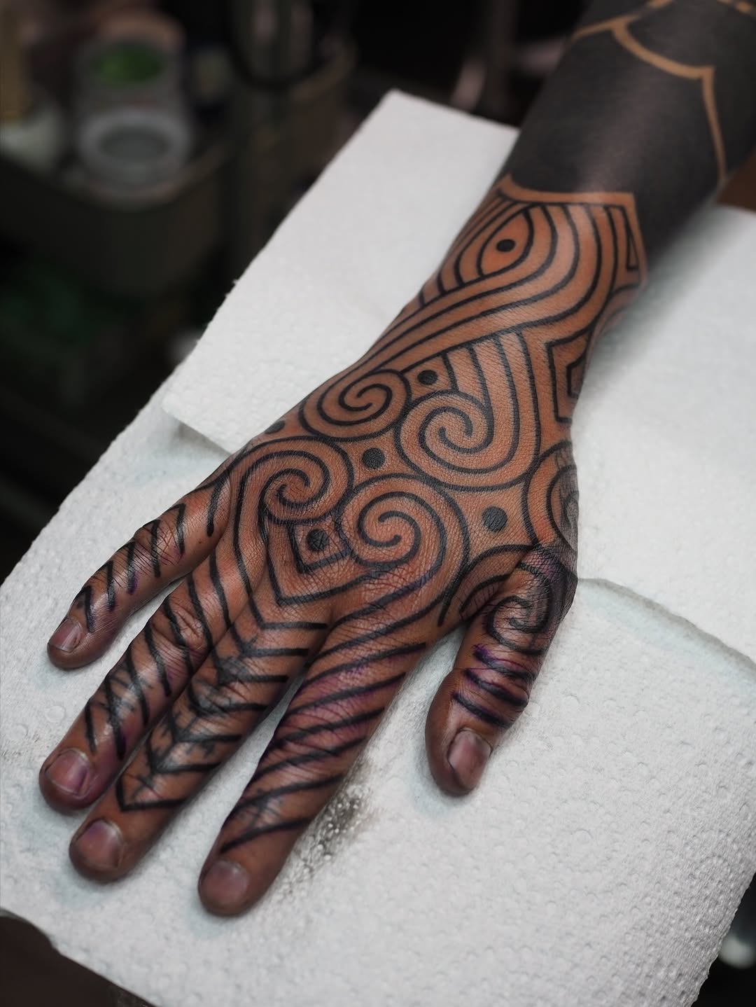 Intricate blackwork ornamental hand tattoo with spiraling geometric patterns